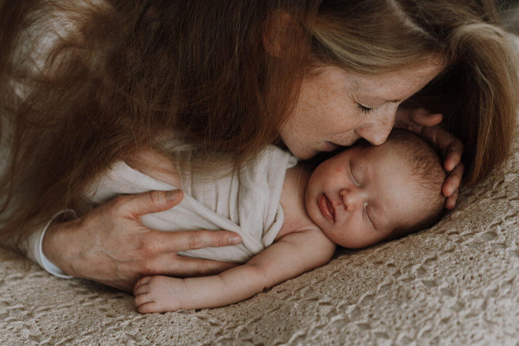 Mutter küsst schlafendes Baby zärtlich, Baby Shooting Bern