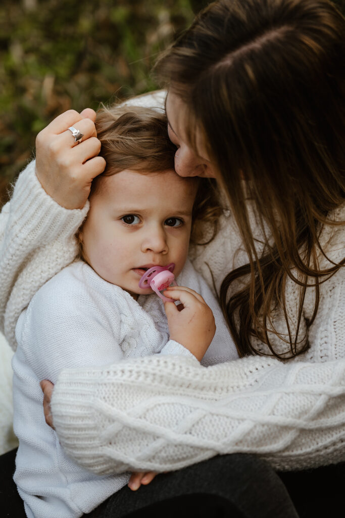 Mutter kuschelt ihre Tochter liebevoll bei Familien Fotoshooting im Wald